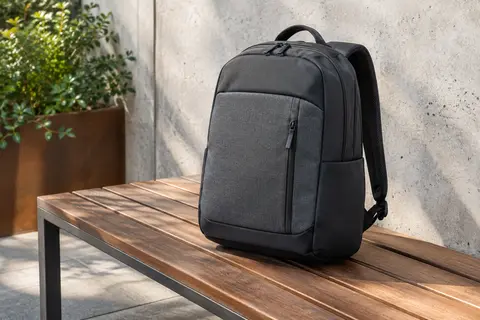 Sac à dos ordinateur Dell EcoLoop noir et gris posé sur un banc en bois dans un décor urbain sobre.