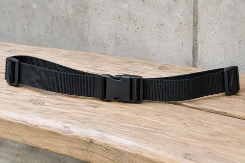 Sangle pectorale en nylon noir de 25 mm avec boucle à clip centrale, posée seule à plat sur un banc en bois clair